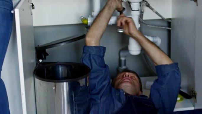 男性水管工在厨房水槽下进行维修