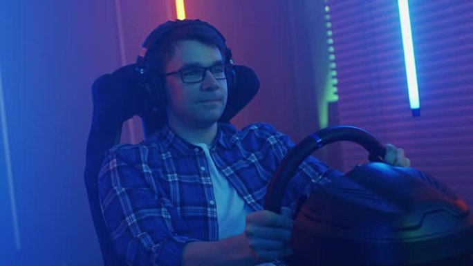职业玩家坐在赛车座椅模拟器驾驶舱与方向盘和玩赛车在线视频游戏。酷驾驶技能。复古照明霓虹灯室。