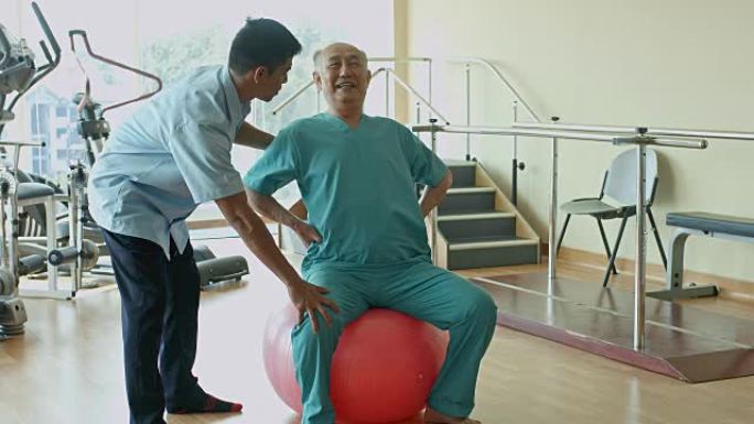 在医院进行理疗的亚洲老人用瑞士球锻炼的实时视频