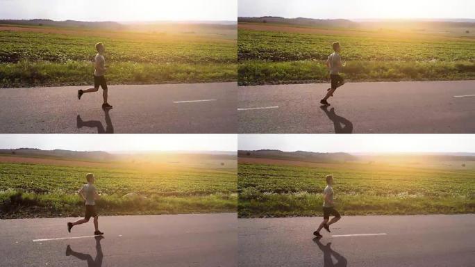 在夕阳背景上在路上奔跑的运动员