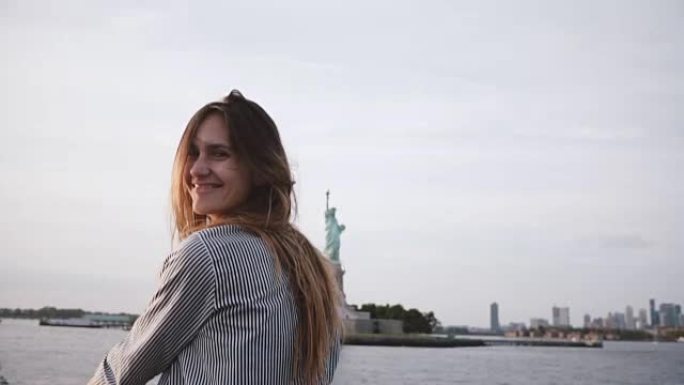 快乐的旅游女人的肖像，头发飞舞，从船上慢动作在自由女神像上享受纽约天际线