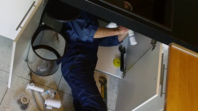 水管工在厨房水槽下进行维修