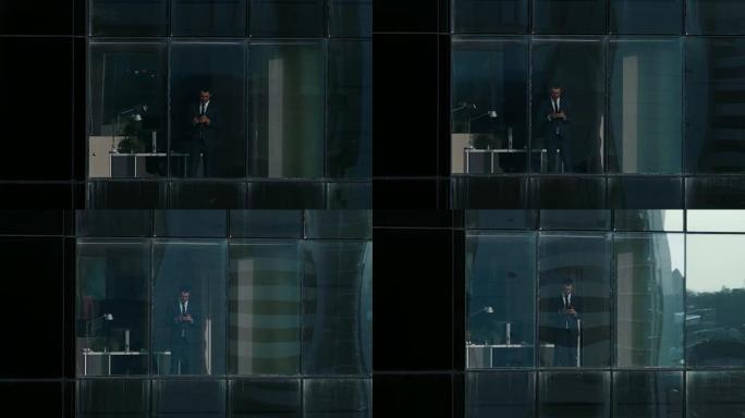 鸟瞰图: 从外面进入办公楼，商人使用手机并站在办公室窗户旁。美丽的飞拍金融商务区摩天大楼。
