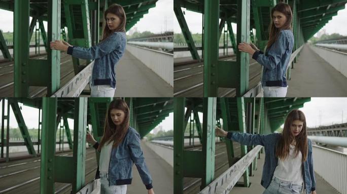 年轻女子在桥下摆姿势。支撑钢柱