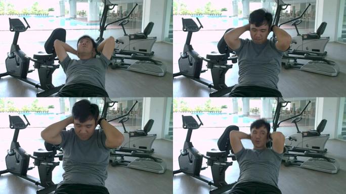 亚洲运动男子在健身房做仰卧起坐。男子在健身馆锻炼身体健康，在健身中心锻炼