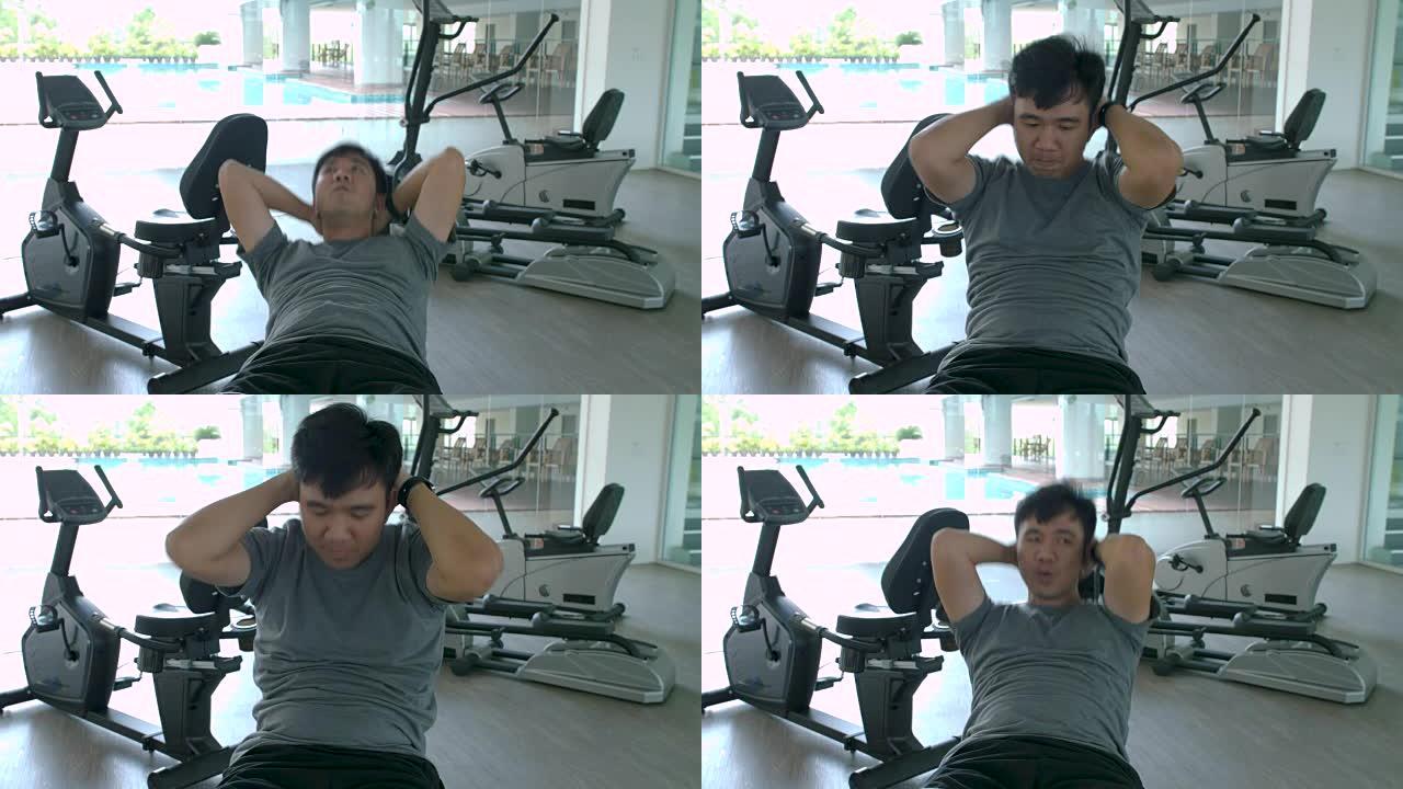 亚洲运动男子在健身房做仰卧起坐。男子在健身馆锻炼身体健康，在健身中心锻炼