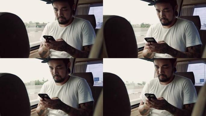 亚洲男子乘坐出租车并在智能手机上上网