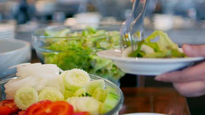 女人手从沙拉吧中选择蔬菜作为健康食品