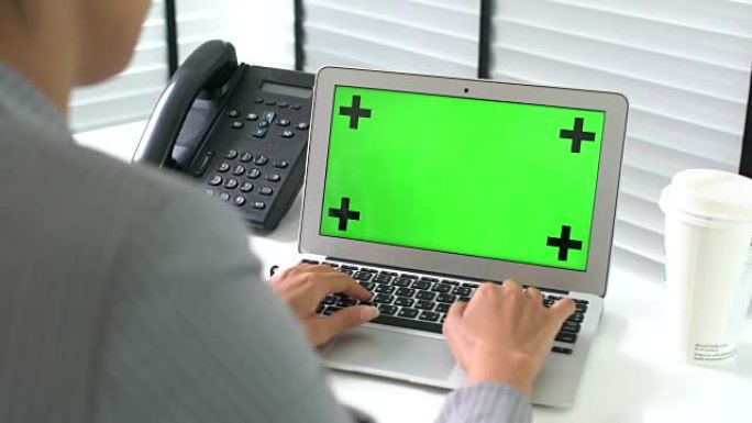 女商人在办公室用绿屏笔记本电脑打字
