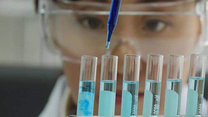 用移液器分析彩色液体以提取试管中的DNA和分子的科学家特写