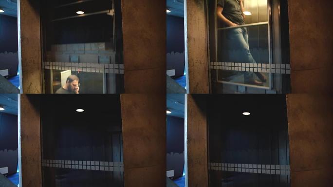 年轻放松的欧洲男子骑在透明的玻璃墙电梯里，在电话里聊天，微笑着