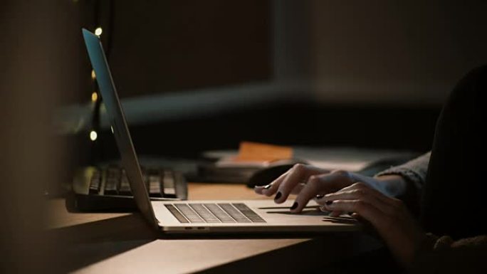 特写女人晚上用笔记本电脑工作。女性手使用笔记本触摸板和触控板。工作狂。4K