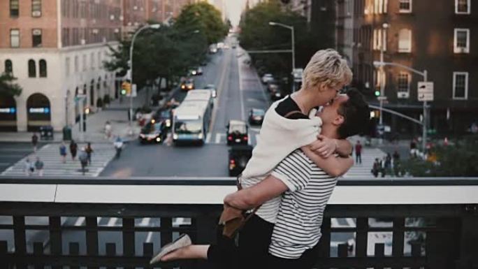 慢动作快乐的西班牙裔男子微笑着高兴地见到欧洲女孩，抱着她，在纽约的一座桥上旋转