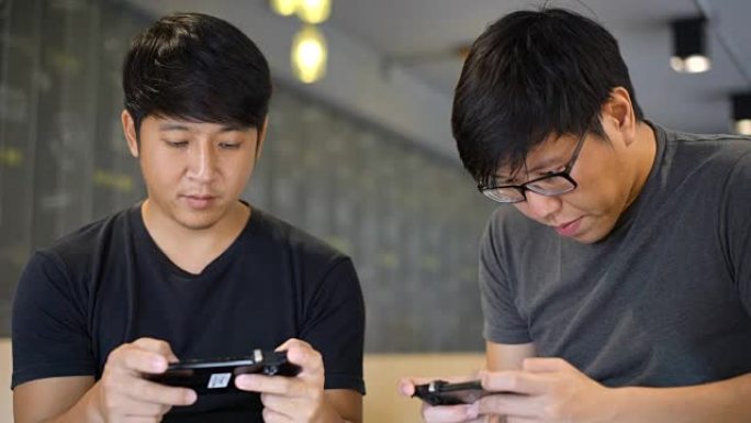 MS两名亚洲男子在玩手机游戏时讨论
