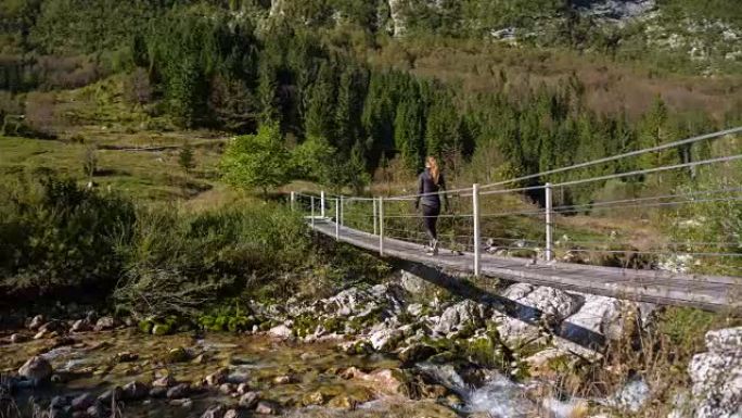 年轻女子越过山间溪流的吊桥