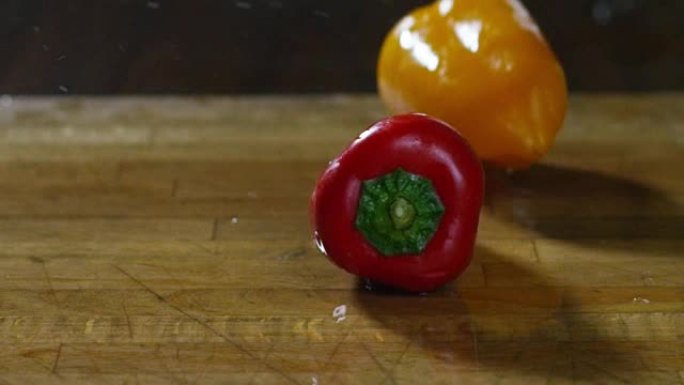 塔利安彩色辣椒在木质砧板上跳跃和弹跳，以极端慢动作达到平衡的位置