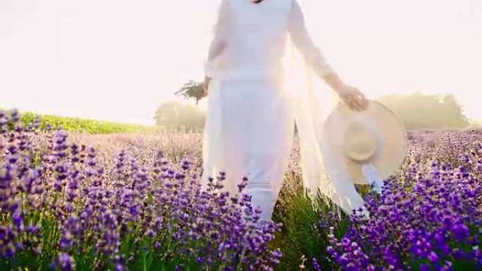 穿着白色连衣裙的女人走在薰衣草的田野里