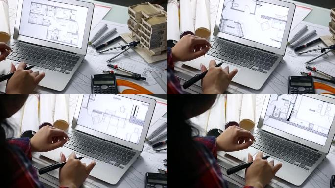 建筑师使用笔记本电脑通过房屋模型和绘图工具检查蓝图