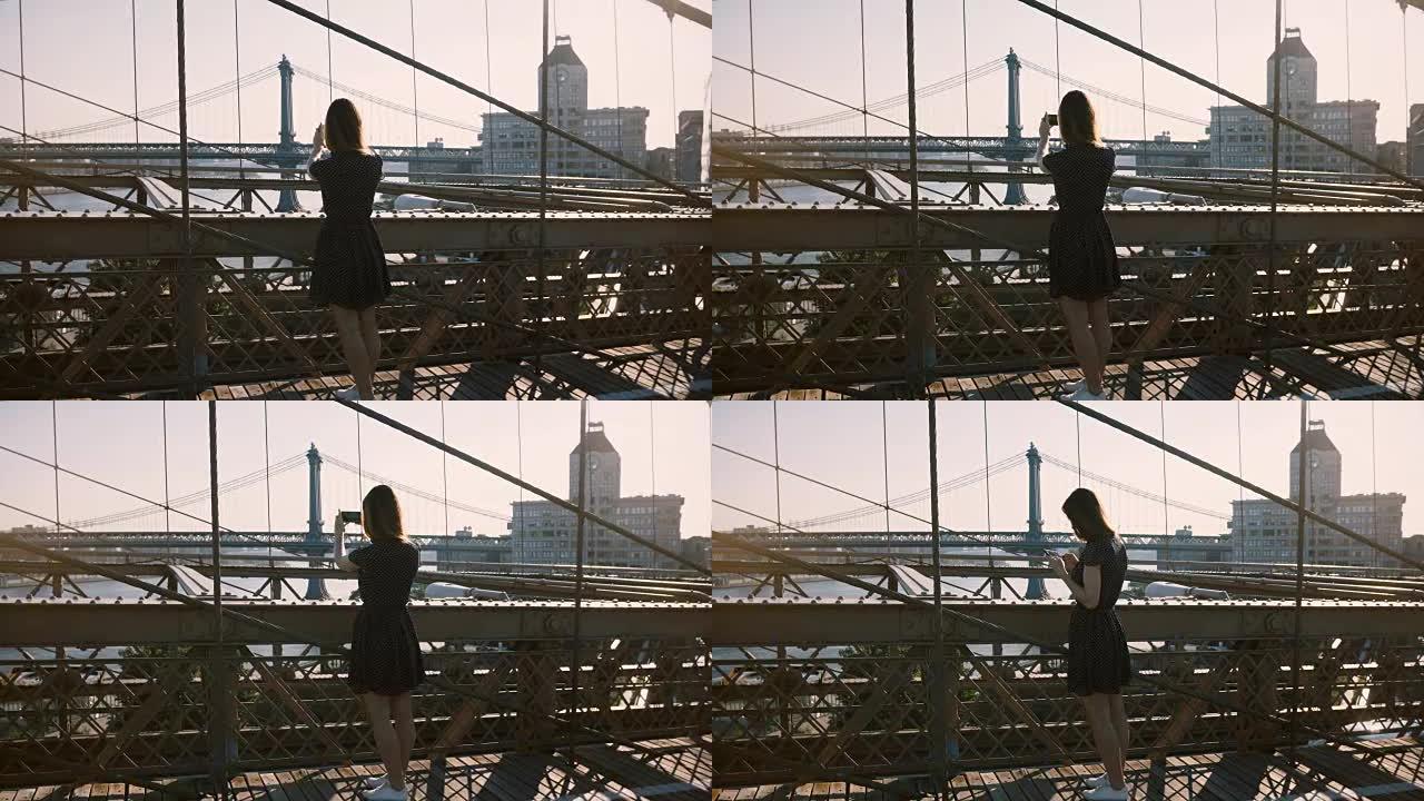美丽的白人妇女沿着纽约布鲁克林大桥行走，停下来拍摄风景4K的智能手机照片