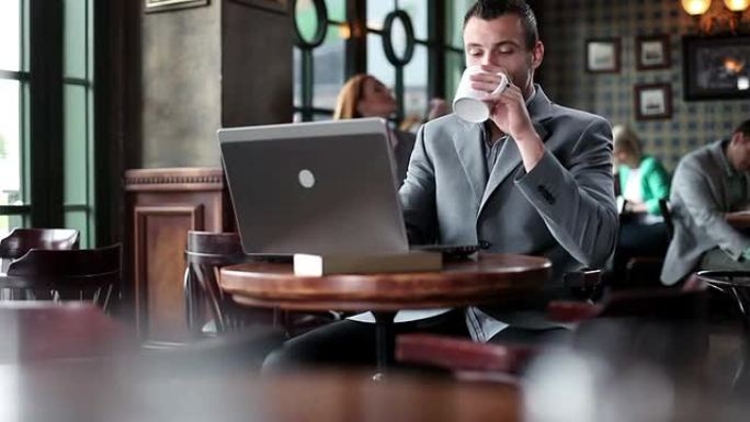 年轻的商人在笔记本电脑上打字，喝咖啡。