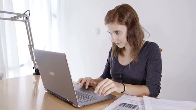年轻女子在笔记本电脑上学习和做作业