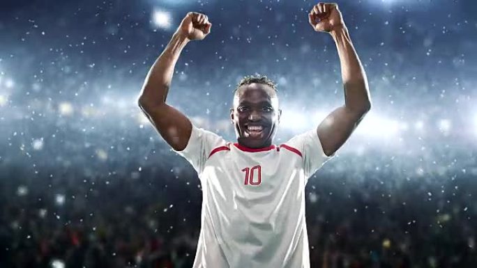 足球运动员庆祝胜利，并在下雪时在专业体育场高兴地举起手臂