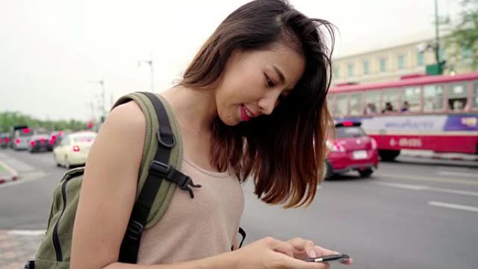 亚洲女性旅游背包客微笑着，使用智能手机独自在泰国曼谷城市街道上度假。
