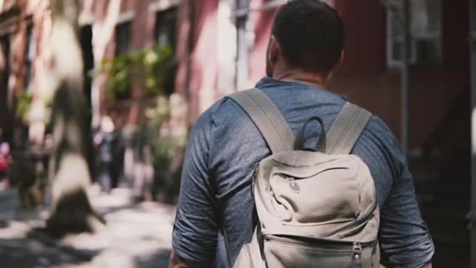 镜头跟随年轻轻松的当地男子背着背包沿着纽约阴暗的夏季布鲁克林街慢动作行走