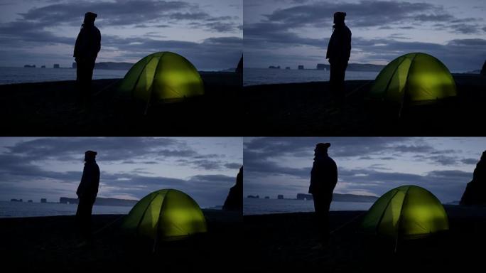 站在野外海滩帐篷旁边的人。