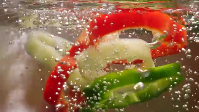 红色，绿色和黄色的甜椒片掉入沸水中