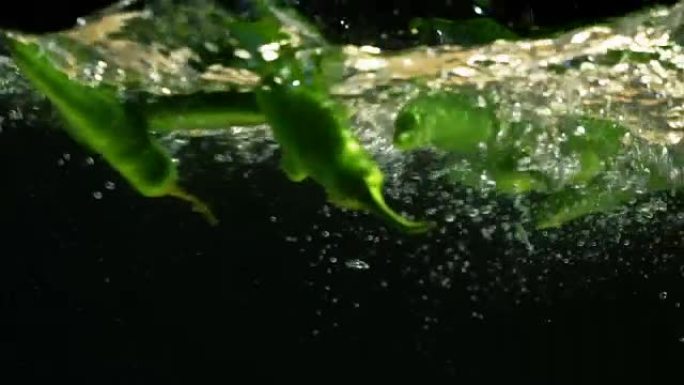 辣椒被扔进一个盛水的容器里。慢动作视频。