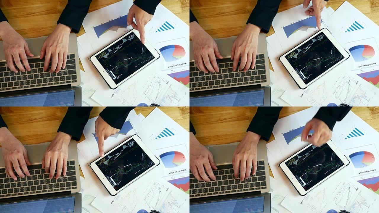 使用数字平板电脑和图表图表在笔记本电脑上工作的商务人士的俯视图