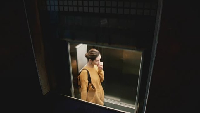 在一个大办公楼的透明玻璃电梯里骑自行车的年轻迷人的白人妇女的景色