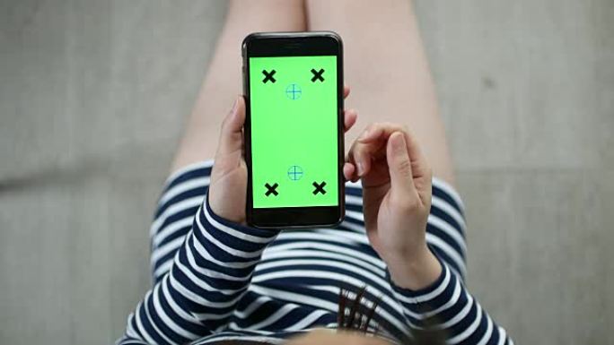 使用智能手机的女性上方视图，绿色屏幕