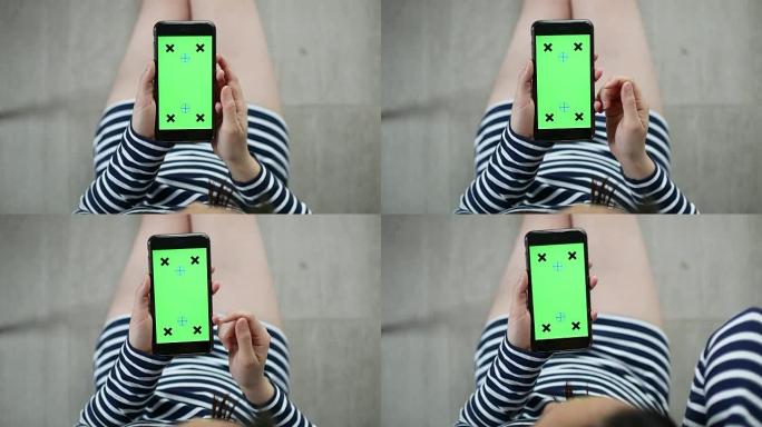 使用智能手机的女性上方视图，绿色屏幕