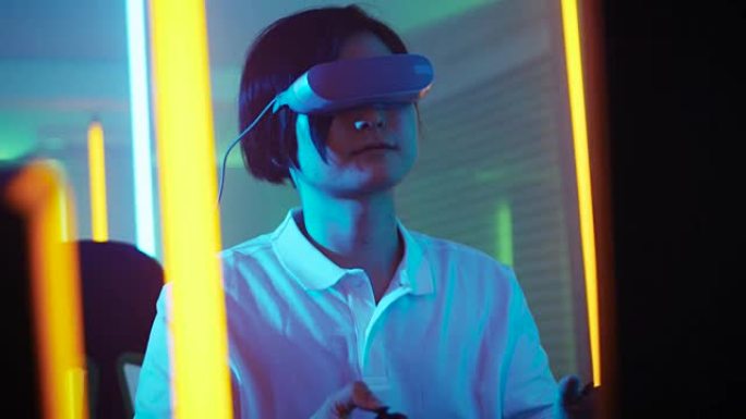 东亚职业玩家戴上虚拟现实耳机，用操纵杆/控制器玩在线视频游戏。房间里很酷的复古霓虹灯颜色。