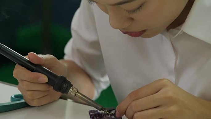 女电子工程师正在她的车间焊接电板。女学生正在教室里学习电子产品和焊接。