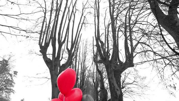 带着红色心形气球的女孩在公园里等待