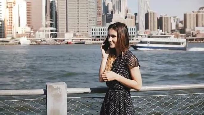 美丽的长头发的年轻高加索女孩沿着纽约，曼哈顿的天际线打电话聊天
