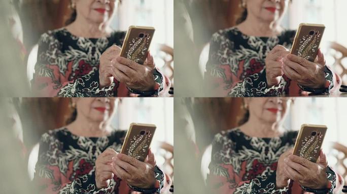 老年亚洲妇女在家中使用智能手机