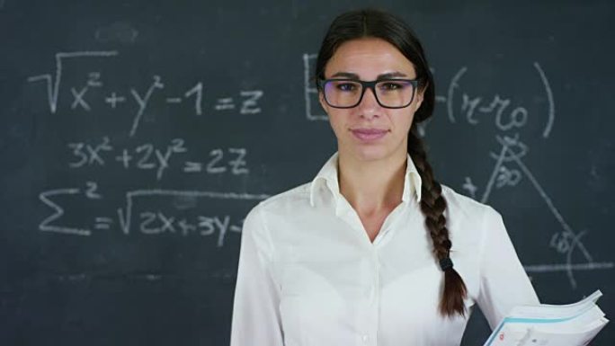 一个美丽的女孩，老师或学生的肖像解决了例子，公式，黑色板上的三角形，黑色背景上的三角形。