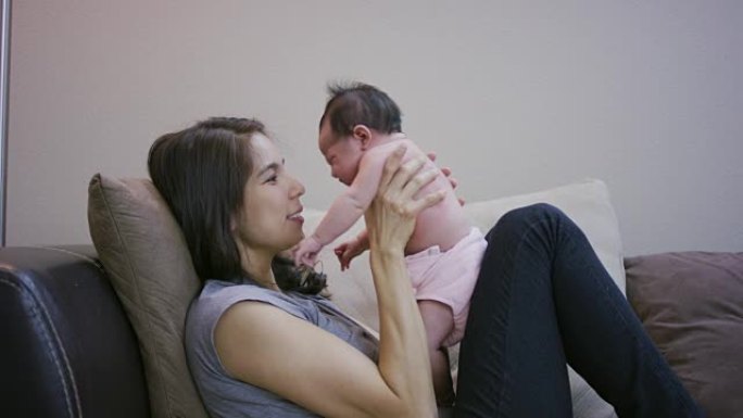 西班牙裔母亲将新生婴儿抱在沙发上
