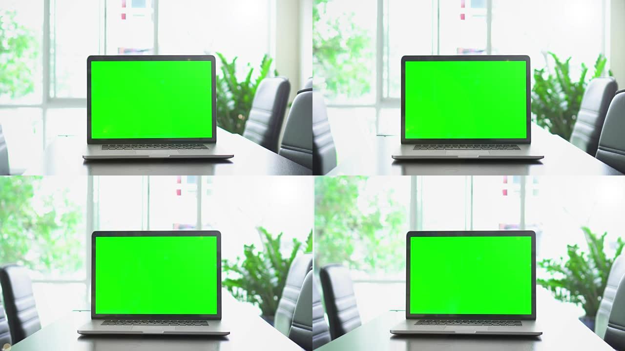 办公桌上绿色屏幕笔记本电脑屏幕的办公室镜头，多莉镜头