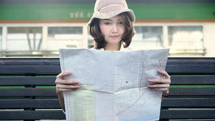 旅行者背包客亚洲女人在泰国曼谷旅行。快乐的年轻女性方向，旅行前在火车站看位置图。