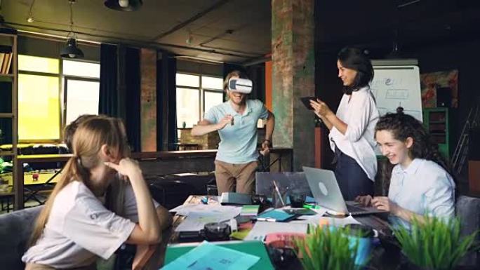 上班族正在享受虚拟现实眼镜的乐趣，男人戴着它们玩跑步和跳跃的游戏，女人正在使用平板电脑和笔记本电脑并