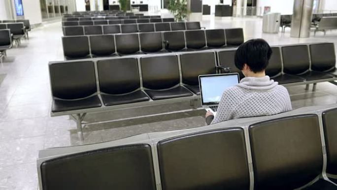 一名女子在机场候机室使用笔记本电脑