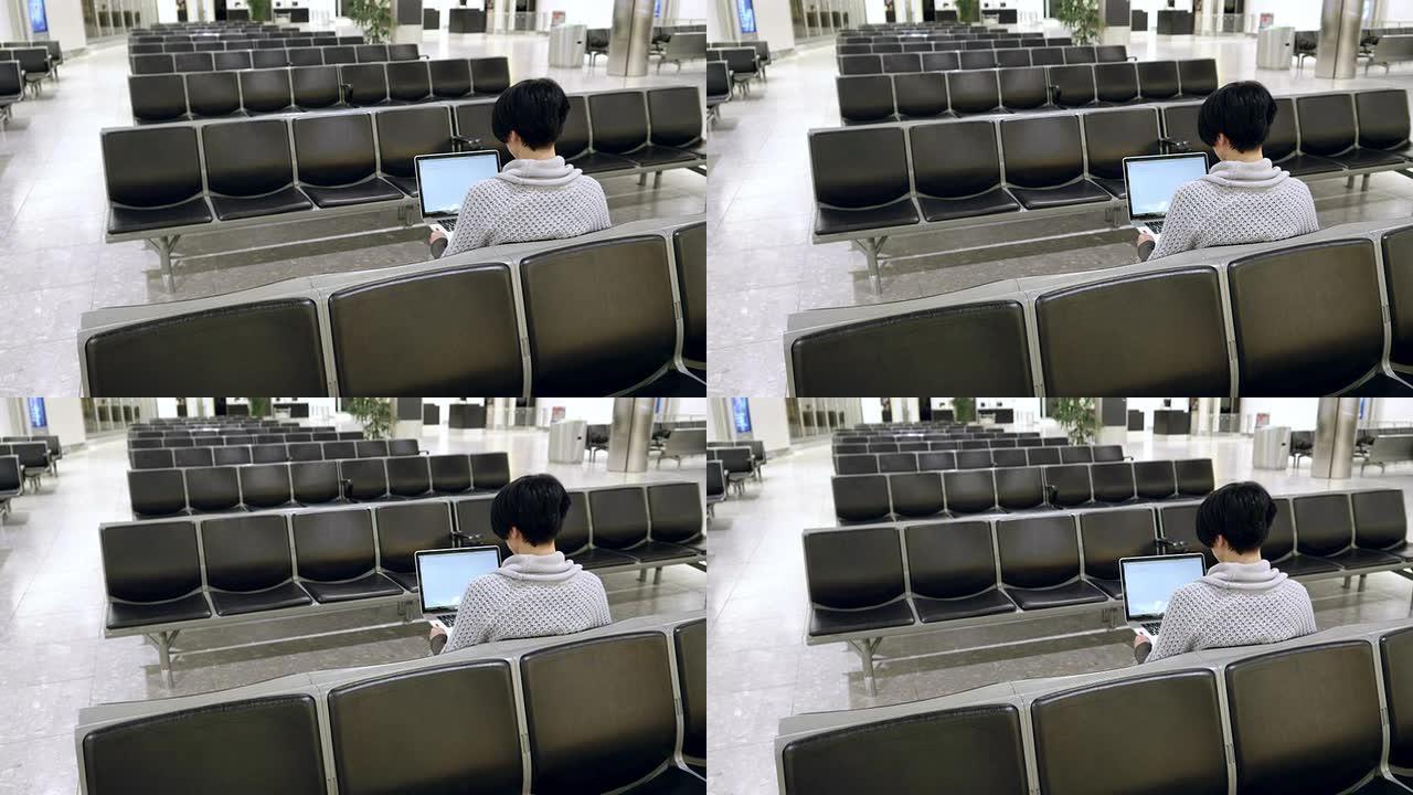 一名女子在机场候机室使用笔记本电脑