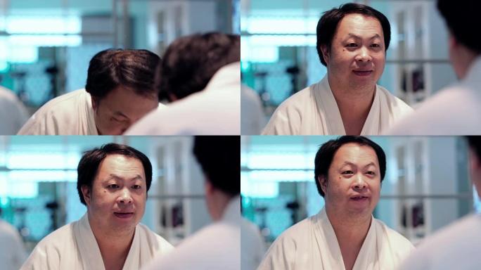 4k镜头的特写镜头亚洲男子在早上在浴室用牙刷刷牙后在镜子前微笑，当在豪华酒店的卧室，生活方式和休闲概