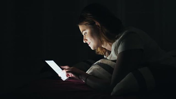 女人睡前使用数字平板电脑。