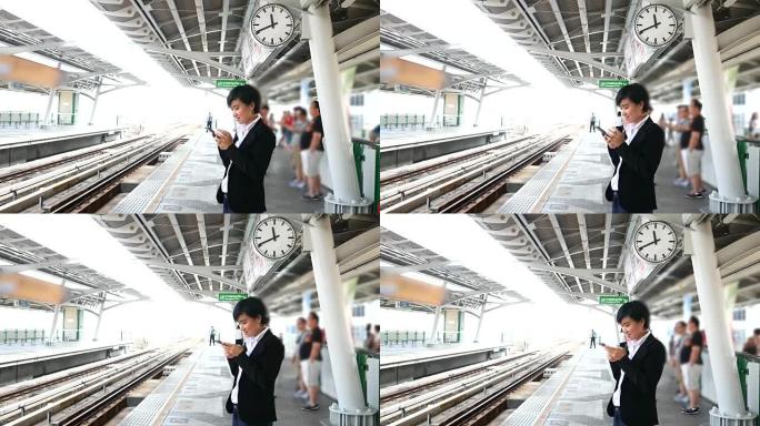 4k: 等待火车并使用智能手机的妇女。